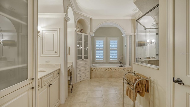 bathroom with tile patterned flooring, vanity, a relaxing tiled tub, and ornamental molding