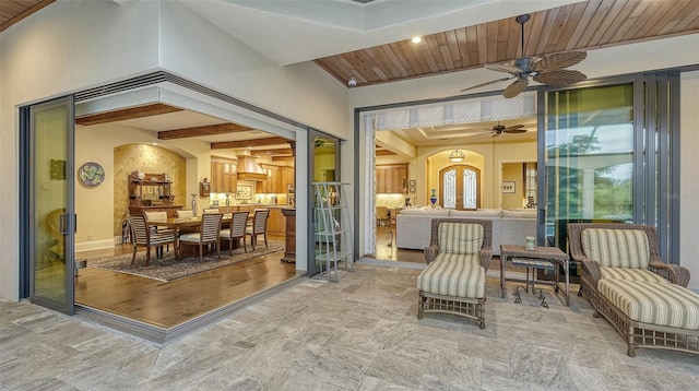 sunroom / solarium featuring beamed ceiling, ceiling fan, and wood ceiling