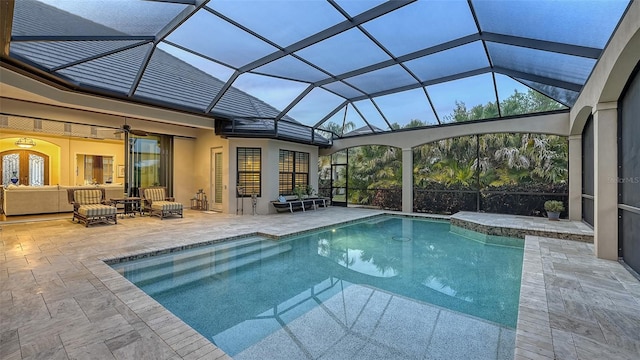 view of pool with outdoor lounge area, ceiling fan, a patio area, and a lanai