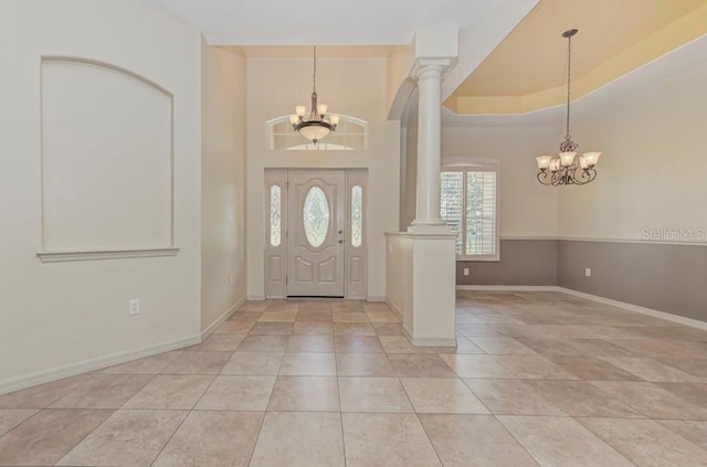 tiled foyer featuring decorative columns and a chandelier