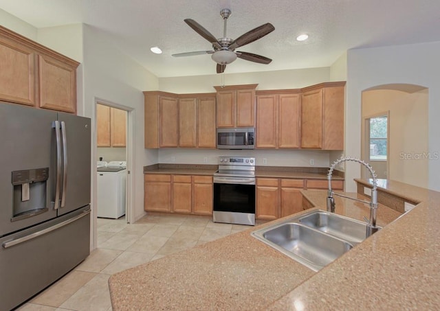 kitchen featuring light tile patterned floors, appliances with stainless steel finishes, ceiling fan, washer and dryer, and sink