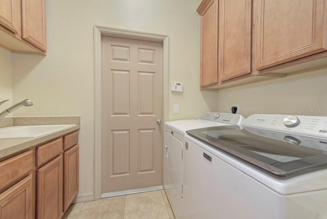 laundry room featuring light tile patterned flooring, cabinets, sink, and washer and clothes dryer