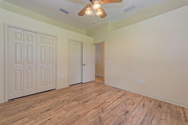 unfurnished bedroom featuring light hardwood / wood-style flooring, two closets, and ceiling fan