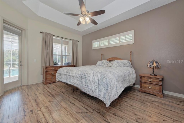 bedroom with light hardwood / wood-style flooring, ceiling fan, multiple windows, and access to exterior