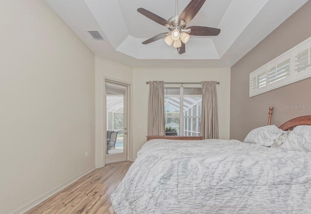 bedroom featuring light hardwood / wood-style floors, a tray ceiling, and ceiling fan