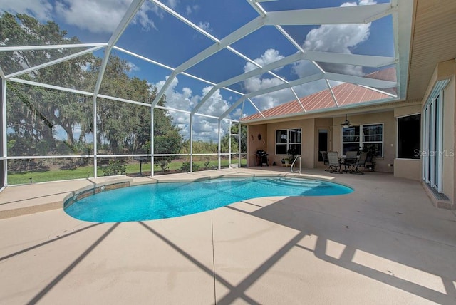 view of swimming pool with a patio area, glass enclosure, and ceiling fan