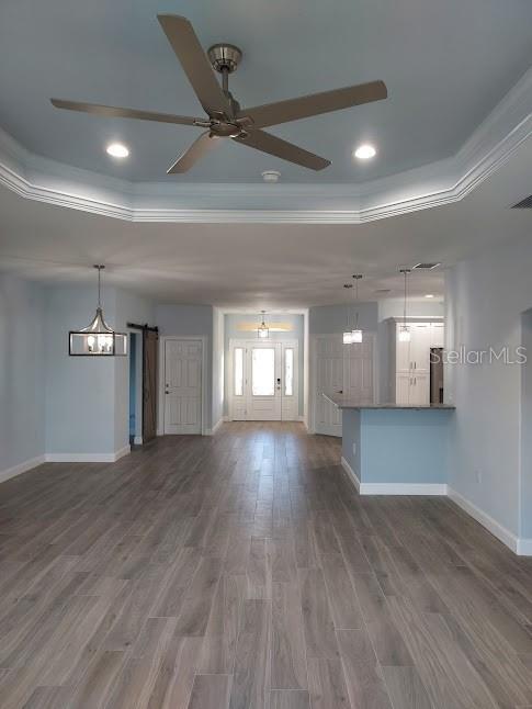 unfurnished living room featuring ornamental molding, a tray ceiling, and dark hardwood / wood-style floors