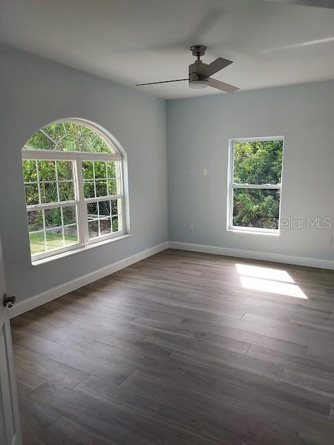 unfurnished room with ceiling fan and dark hardwood / wood-style flooring