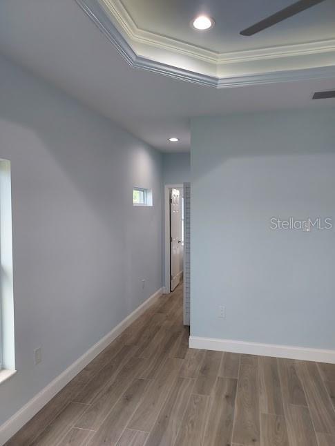 spare room with hardwood / wood-style flooring, a tray ceiling, and ornamental molding