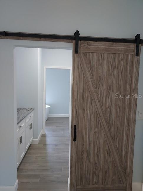 hall with a barn door and hardwood / wood-style floors