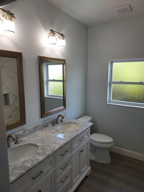 bathroom featuring plenty of natural light, hardwood / wood-style floors, vanity, and toilet