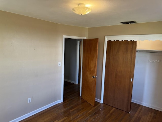 unfurnished bedroom with dark hardwood / wood-style flooring and a closet