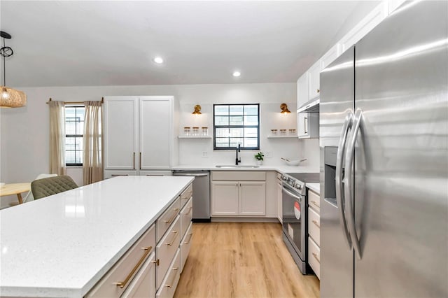 kitchen with stainless steel appliances, decorative light fixtures, a wealth of natural light, and white cabinetry