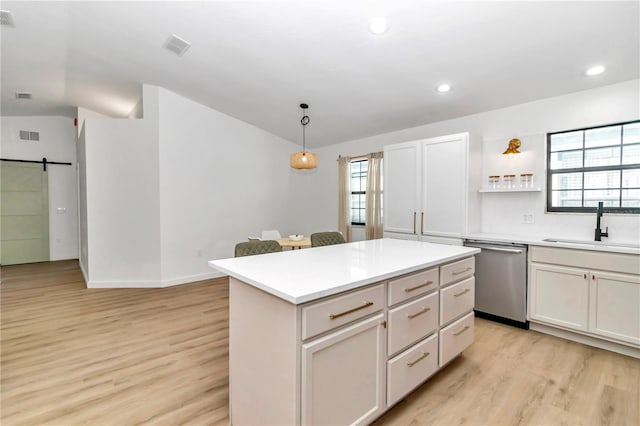 kitchen with a center island, stainless steel dishwasher, sink, a barn door, and decorative light fixtures