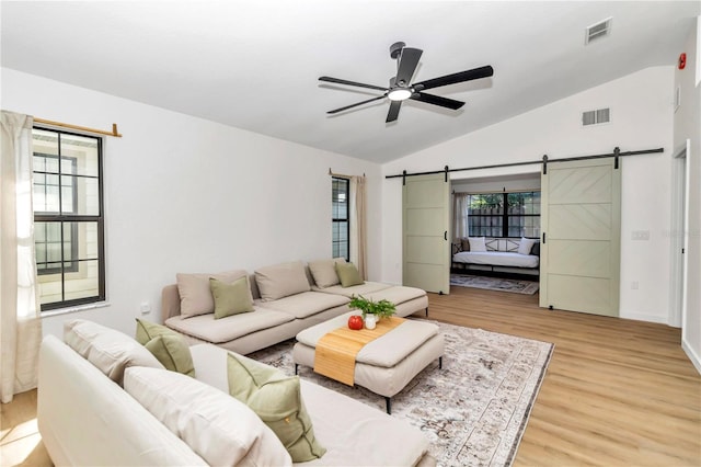 living room with ceiling fan, vaulted ceiling, light hardwood / wood-style flooring, and a healthy amount of sunlight