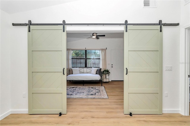 bedroom featuring hardwood / wood-style flooring, lofted ceiling, and a barn door