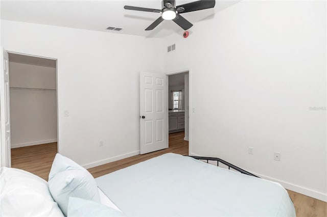 bedroom featuring wood-type flooring, a closet, a walk in closet, and ceiling fan