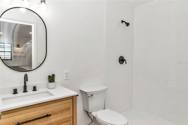 bathroom featuring tiled shower, vanity, and toilet