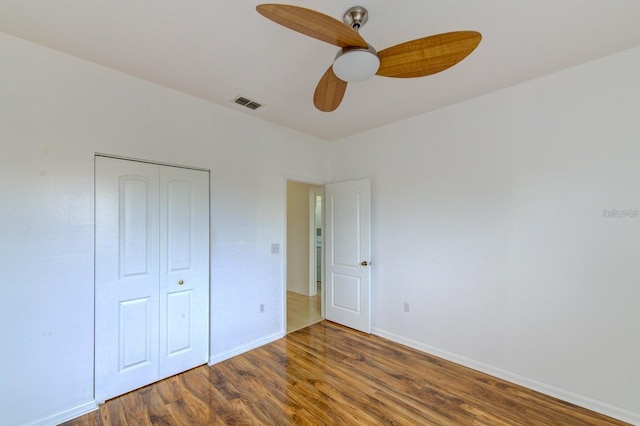 unfurnished bedroom featuring dark hardwood / wood-style flooring, ceiling fan, and a closet