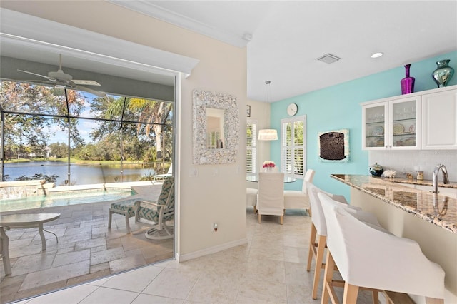 dining area with a water view, ceiling fan, and crown molding