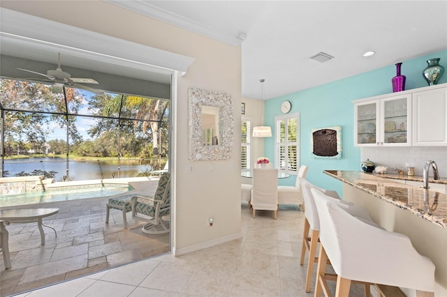 12121 Thornhill Ct, Lakewood Ranch, FL 34202 - dining room with a water view, a ceiling fan, and baseboards