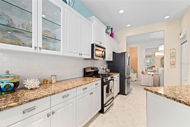 12121 Thornhill Ct, Lakewood Ranch, FL 34202 - kitchen featuring stainless steel appliances, white cabinetry, glass insert cabinets, light stone countertops, and recessed lighting