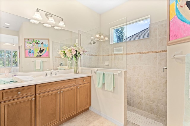 bathroom with tile patterned flooring, vanity, a healthy amount of sunlight, and tiled shower