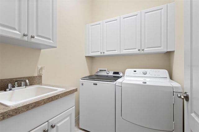 laundry area featuring cabinets, separate washer and dryer, and sink