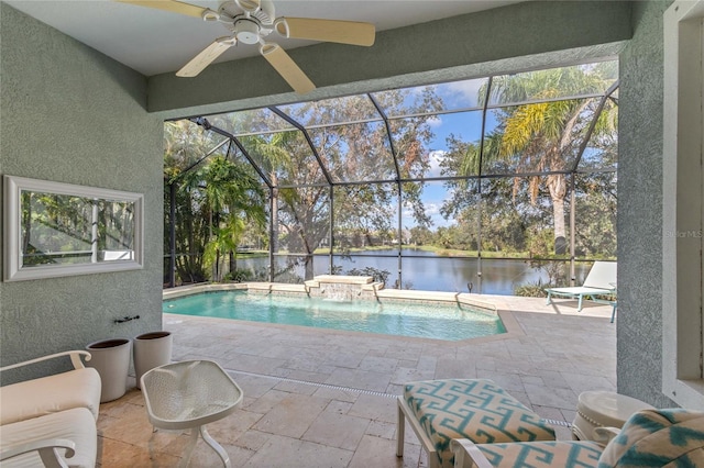 view of pool with glass enclosure, a water view, pool water feature, ceiling fan, and a patio area