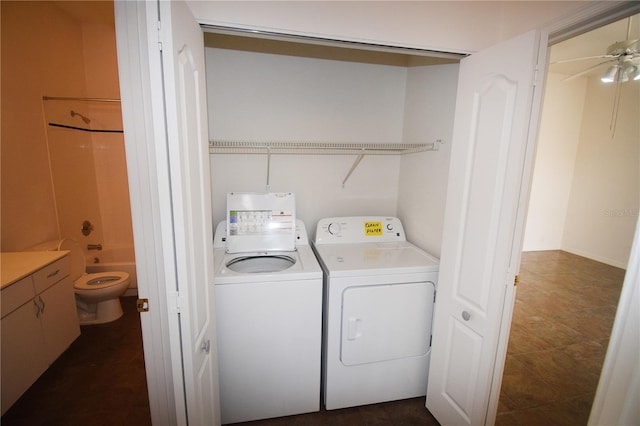 clothes washing area featuring ceiling fan, washing machine and clothes dryer, and dark tile patterned floors