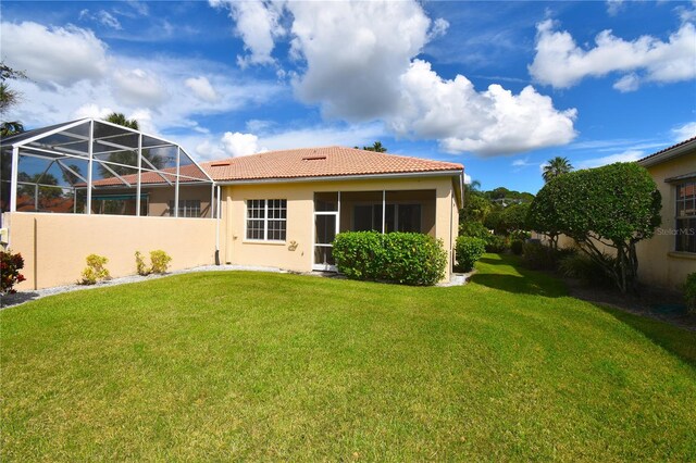 back of house featuring a yard and glass enclosure