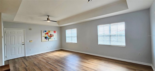 empty room featuring ceiling fan, hardwood / wood-style floors, and a tray ceiling