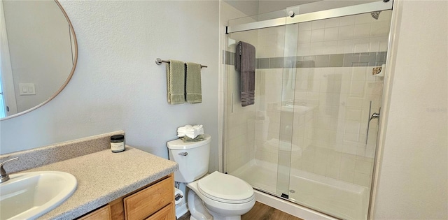 bathroom with wood-type flooring, toilet, a shower with door, and vanity