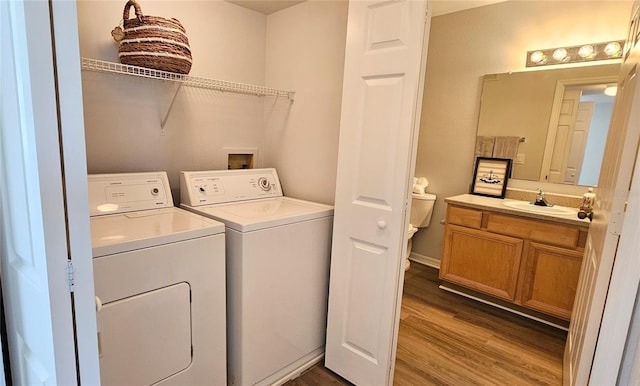 clothes washing area featuring sink, wood-type flooring, and washer and dryer