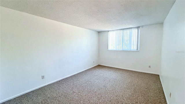 carpeted empty room featuring a textured ceiling