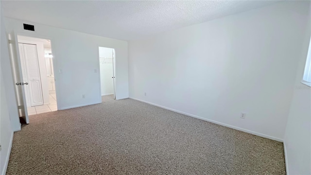 spare room featuring light carpet and a textured ceiling