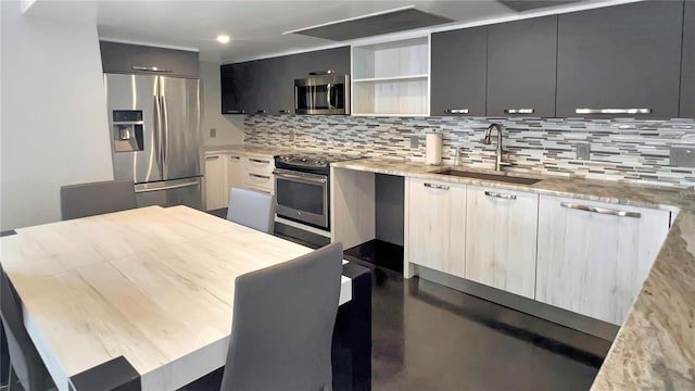 kitchen with light stone counters, stainless steel appliances, tasteful backsplash, and sink