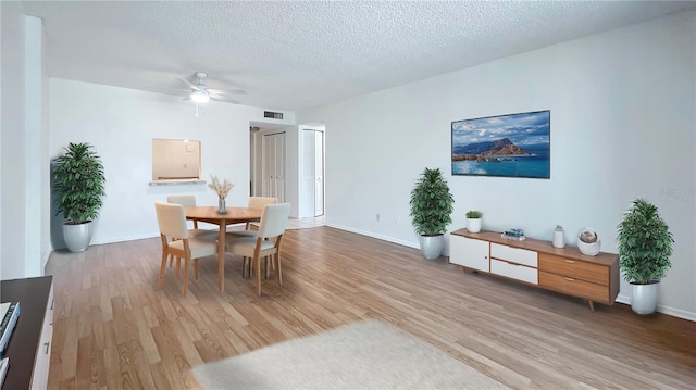 dining room featuring light hardwood / wood-style floors, a textured ceiling, and ceiling fan