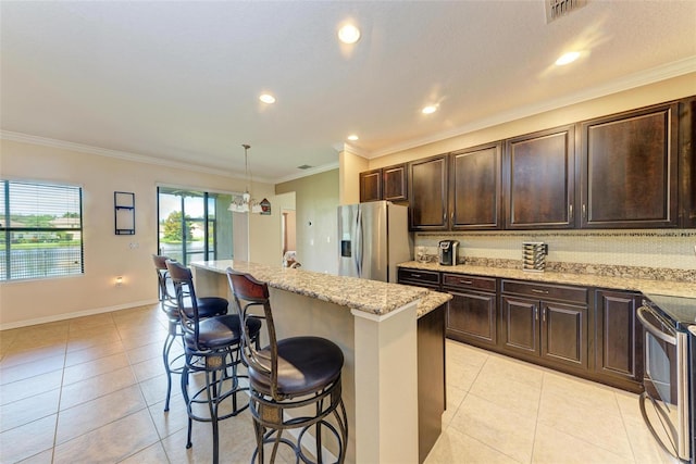 kitchen featuring appliances with stainless steel finishes, a center island, hanging light fixtures, decorative backsplash, and a breakfast bar