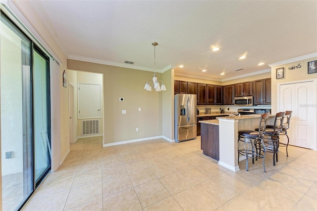 kitchen featuring crown molding, a kitchen bar, decorative light fixtures, appliances with stainless steel finishes, and light stone counters