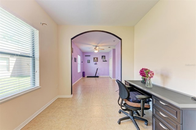 tiled office space featuring built in desk, ceiling fan, and a healthy amount of sunlight