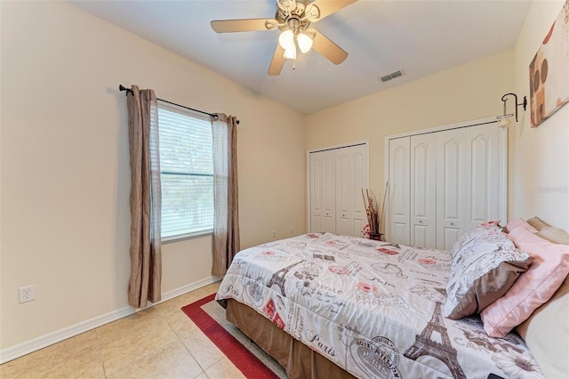 bedroom featuring two closets, light tile patterned flooring, and ceiling fan