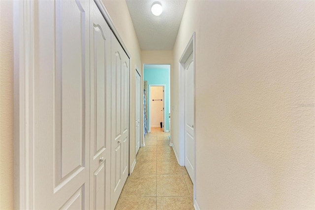 corridor featuring a textured ceiling and light tile patterned flooring