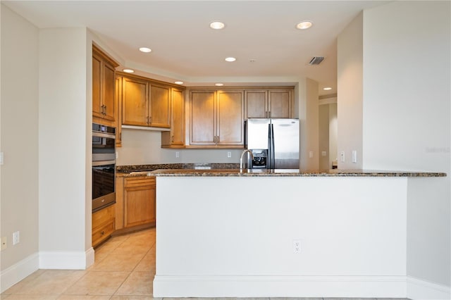 kitchen featuring sink, appliances with stainless steel finishes, light tile patterned flooring, and dark stone countertops