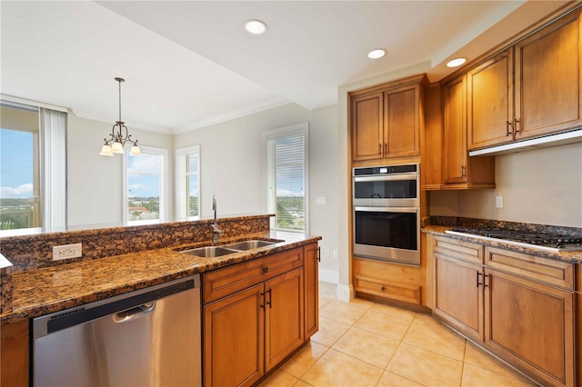 kitchen featuring hanging light fixtures, appliances with stainless steel finishes, an inviting chandelier, dark stone countertops, and sink