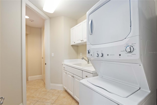 washroom featuring sink, stacked washer / dryer, light tile patterned floors, and cabinets