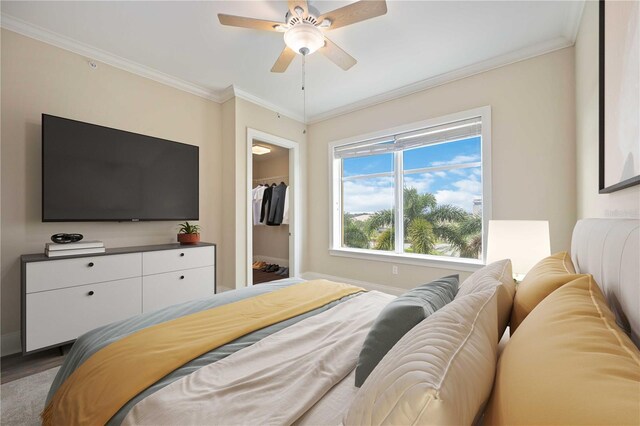 bedroom featuring crown molding, hardwood / wood-style floors, a spacious closet, and ceiling fan