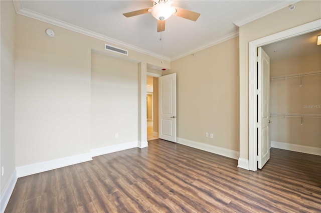 unfurnished bedroom with dark wood-type flooring, crown molding, a closet, and ceiling fan