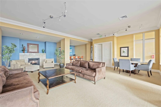 living room featuring rail lighting, crown molding, a premium fireplace, and light colored carpet