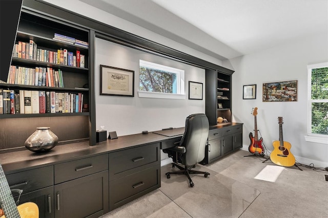 home office with plenty of natural light, light carpet, and built in shelves